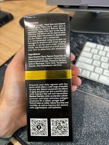 Hand holding a retinol serum box with ingredients and instructions.