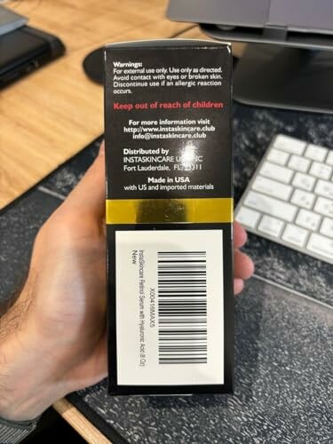 Hand holding skincare product box with warning and barcode